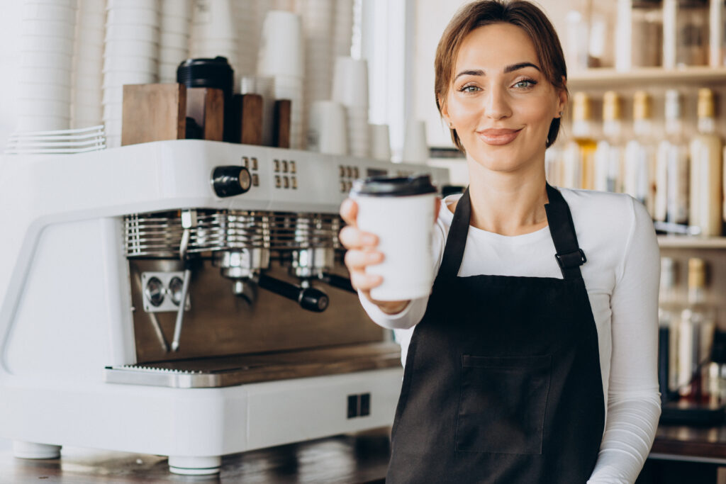 female barista worker in a coffee shop holding coffee cup